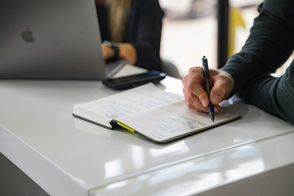 Une main remplit un formulaire sur un carnet
