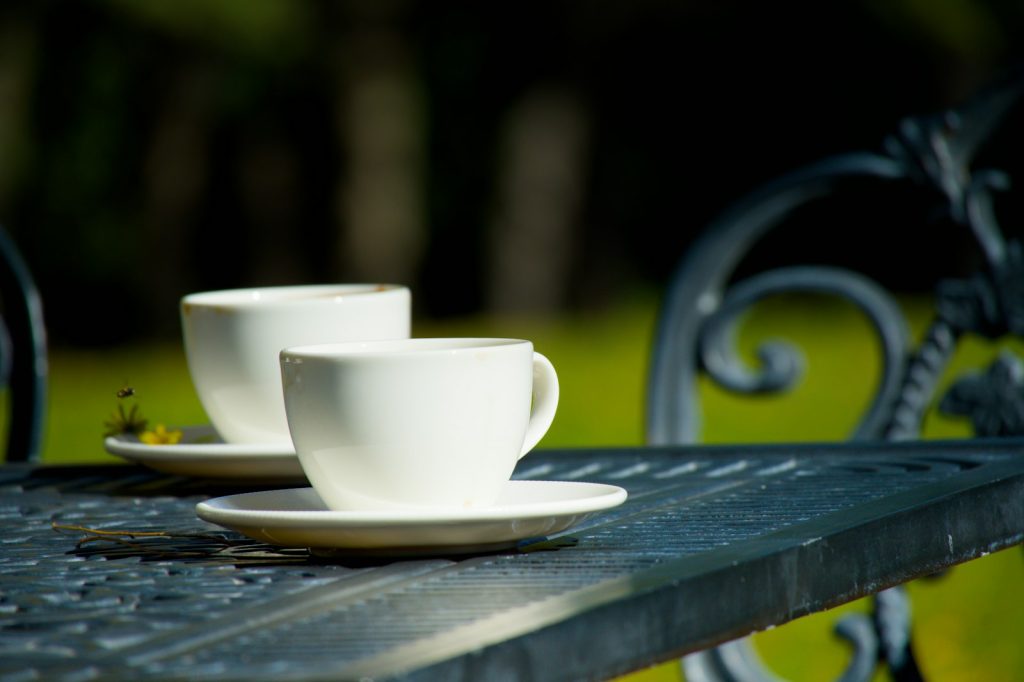 Deux tasses de café posées sur une table de jardin